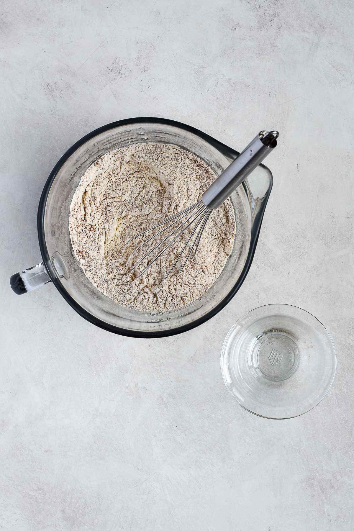 Mixing bowl filled with dry ingredients—flour, baking soda, pumpkin pie spice, and salt—being whisked together for pumpkin chocolate chip cookie bars.