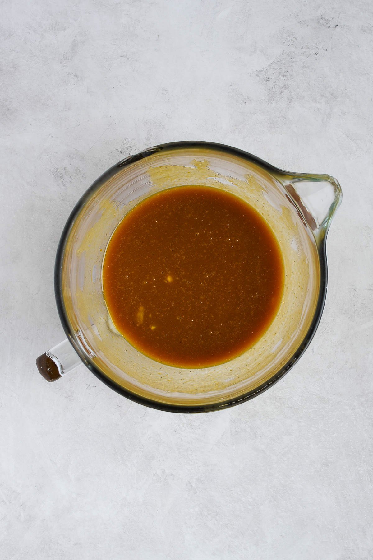 Large glass mixing bowl with melted butter, brown sugar, pumpkin purée, egg, and vanilla mixed into a smooth base for pumpkin cookie bars.