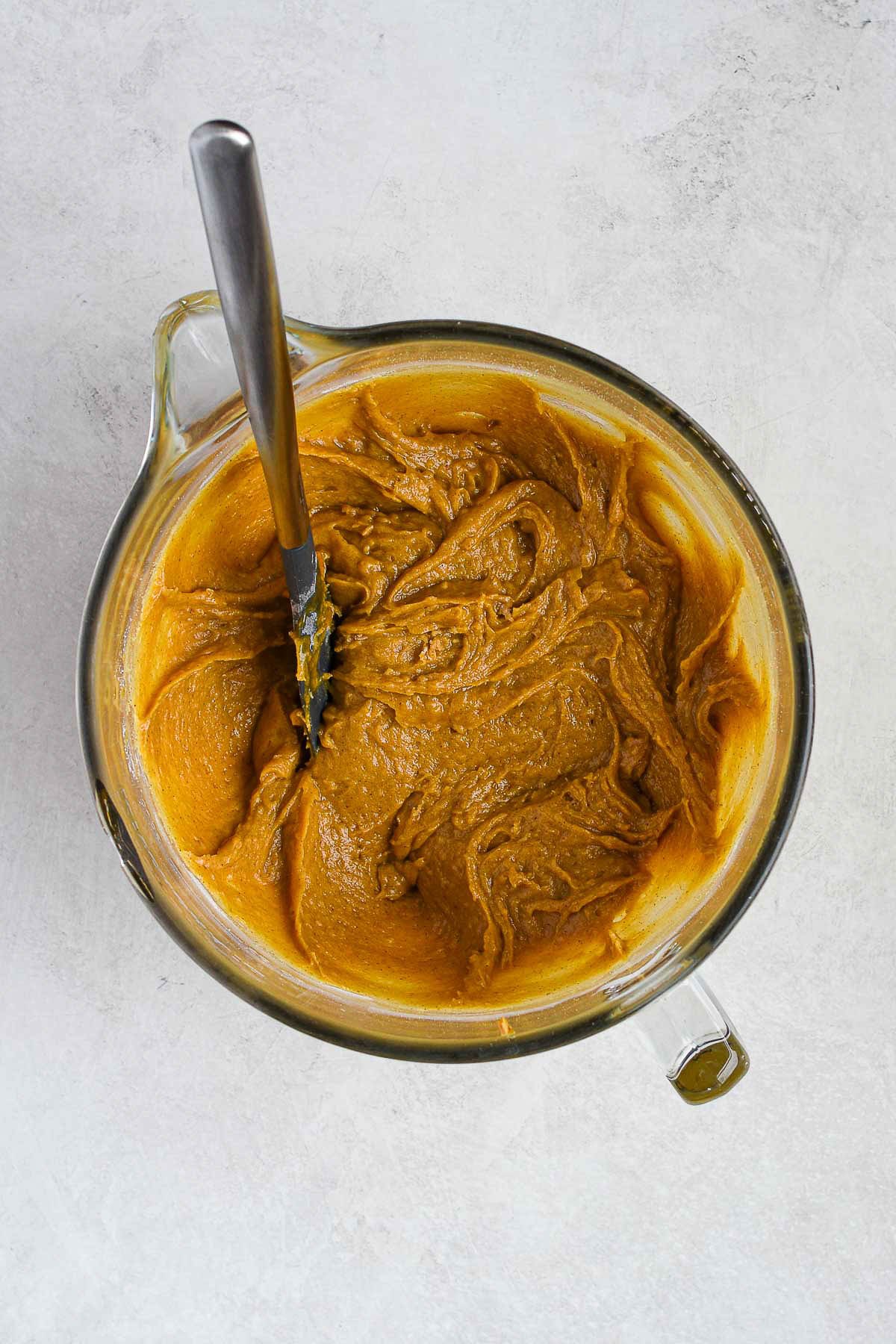 Thick pumpkin cookie bar batter forming in a mixing bowl after combining wet and dry ingredients.