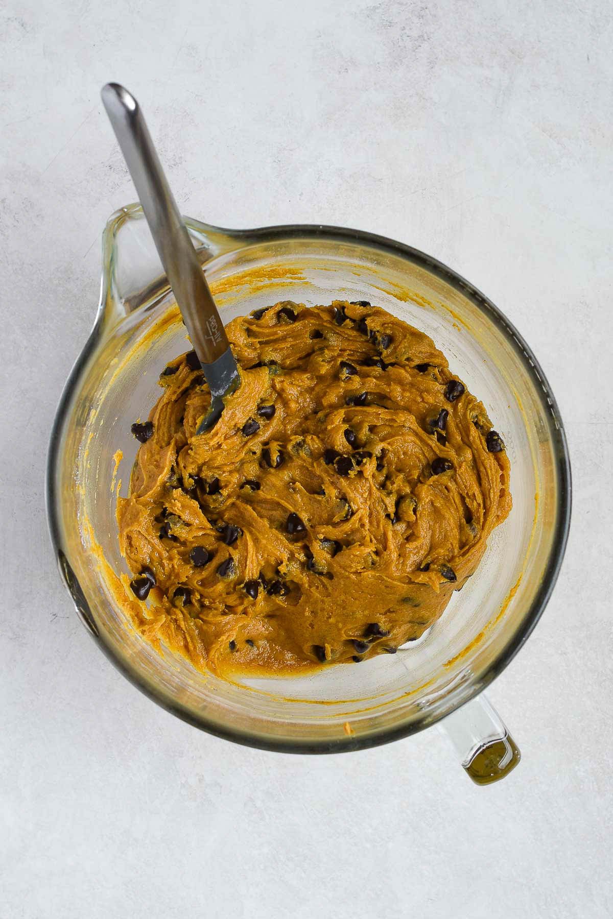 Pumpkin chocolate chip cookie bar batter with dark chocolate chips folded in, ready to be spread into the pan.