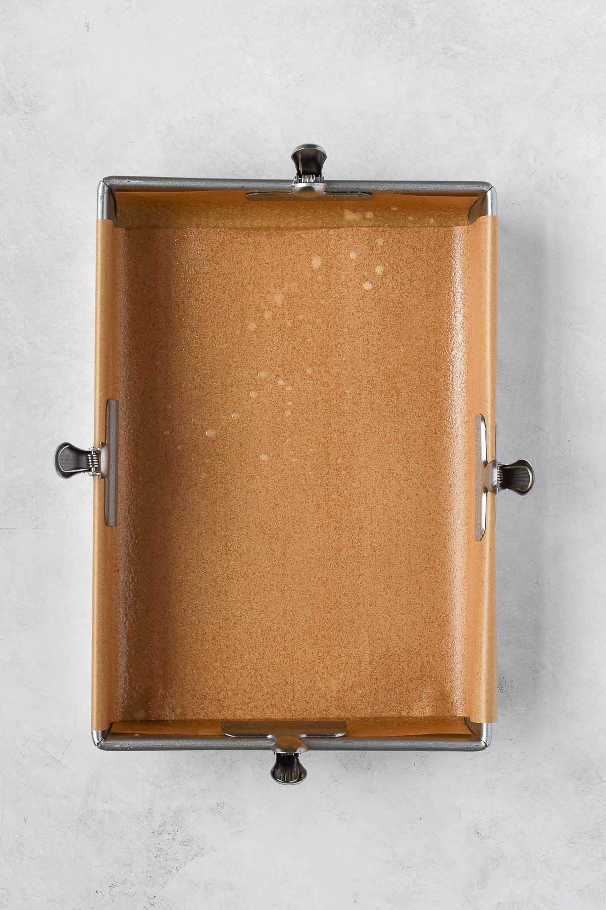 9x13-inch baking pan lined with parchment paper and lightly sprayed with nonstick spray, prepared for baking pumpkin cookie bars.