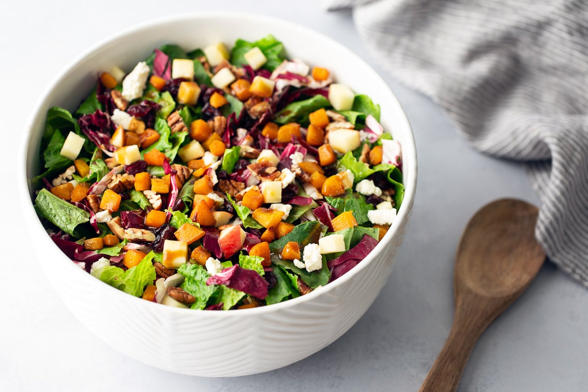 Golden roasted butternut squash cubes in a white bowl ready for roasted squash salad.