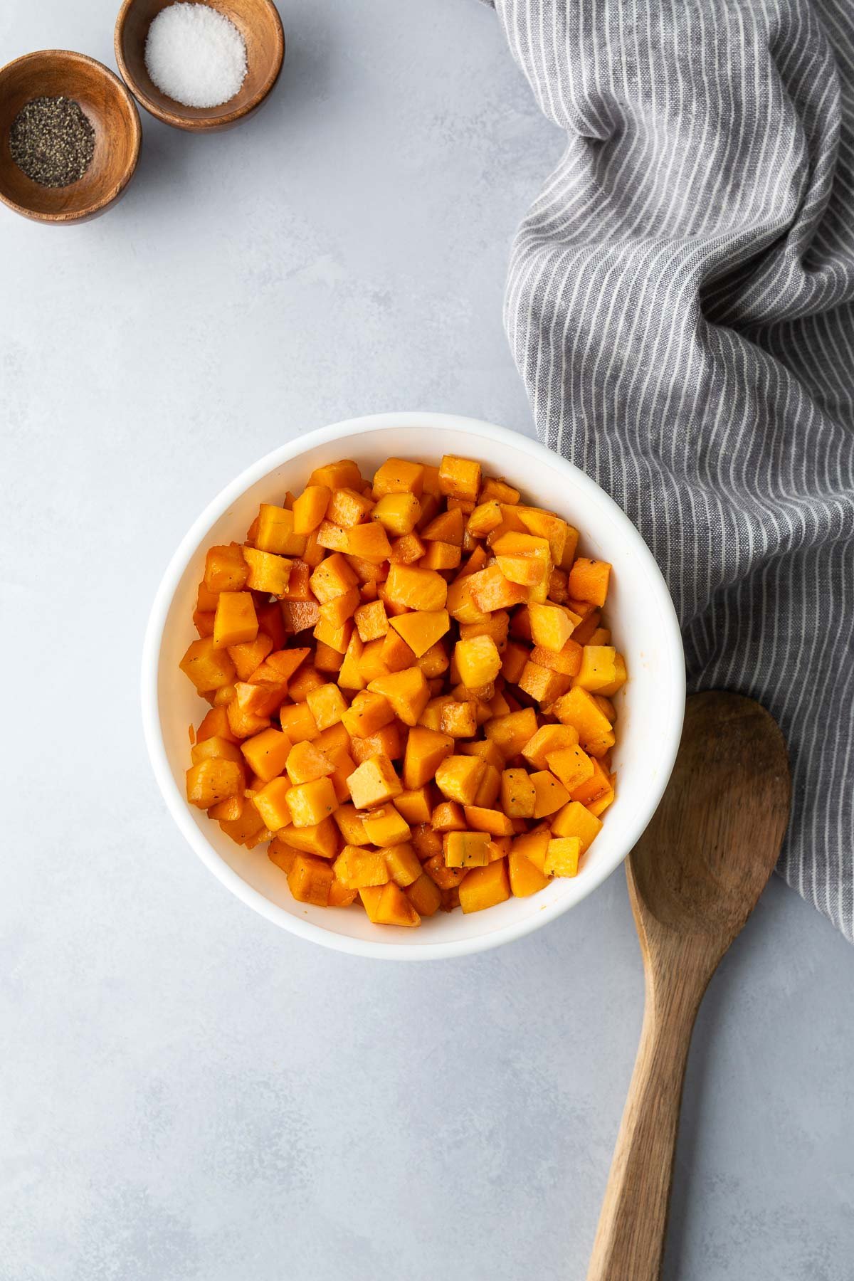 Golden roasted butternut squash cubes in a white bowl ready for roasted squash salad.