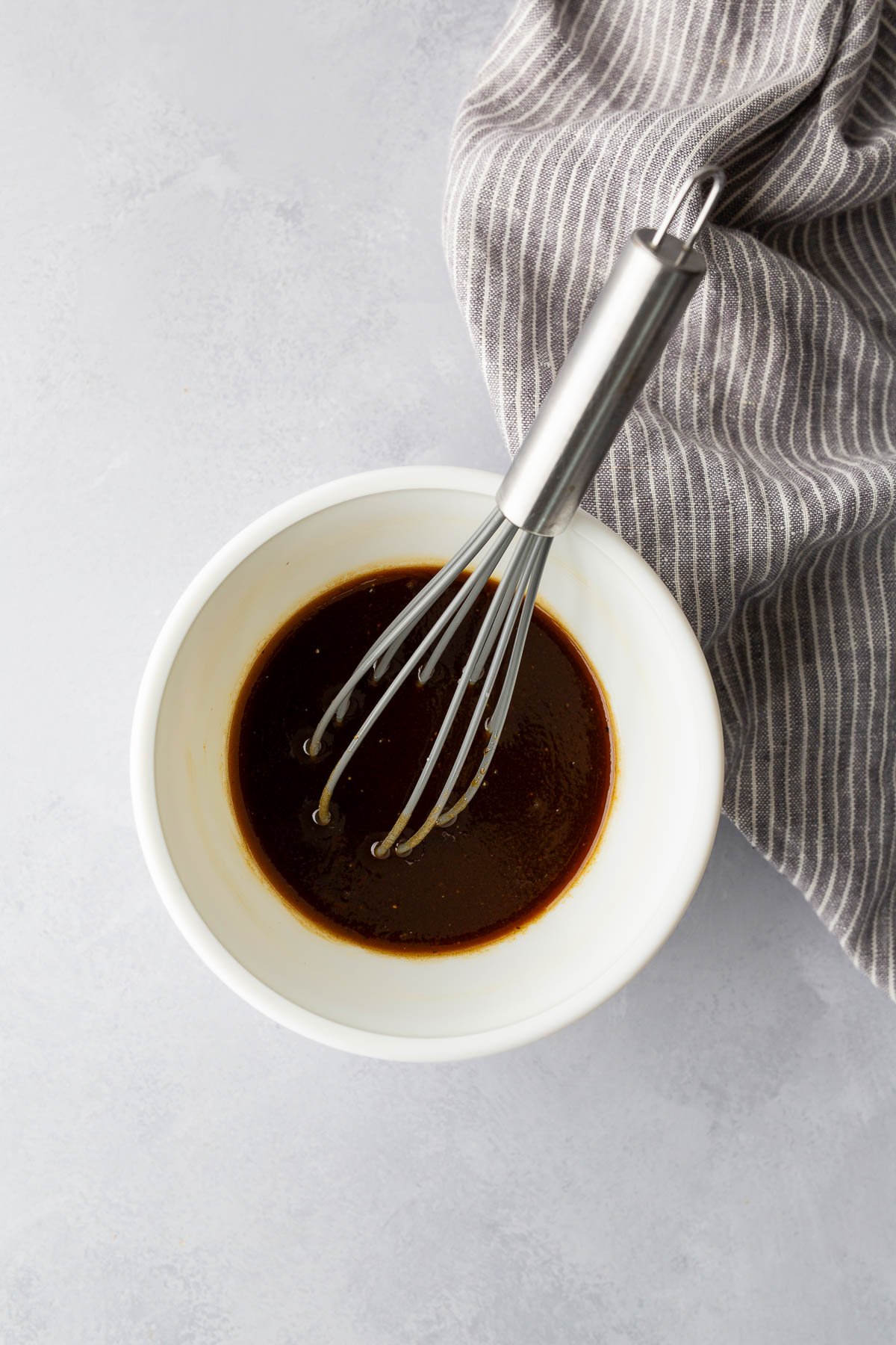 Homemade balsamic vinaigrette dressing with Dijon mustard whisked in a white bowl.