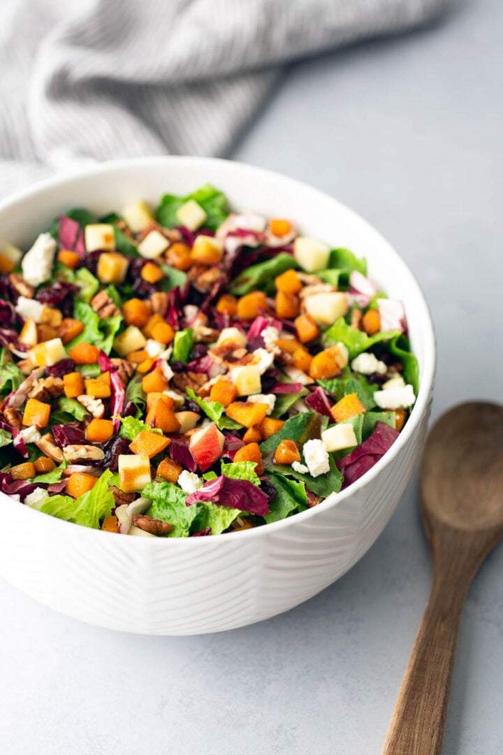 Side view of vibrant roasted butternut squash salad with romaine, radicchio, apples, and feta.
