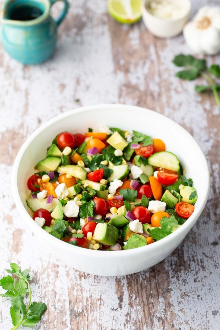 Tomato cucumber avocado and corn salad mixed with red onion, feta, and cilantro.